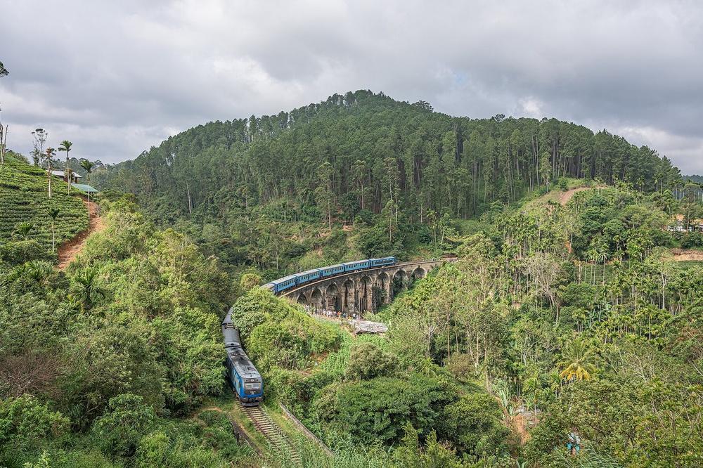 A blue-carriage train on a stone viaduct in the tea hills near Ella A blue-carriage train on a stone viaduct in the tea hills near Ella