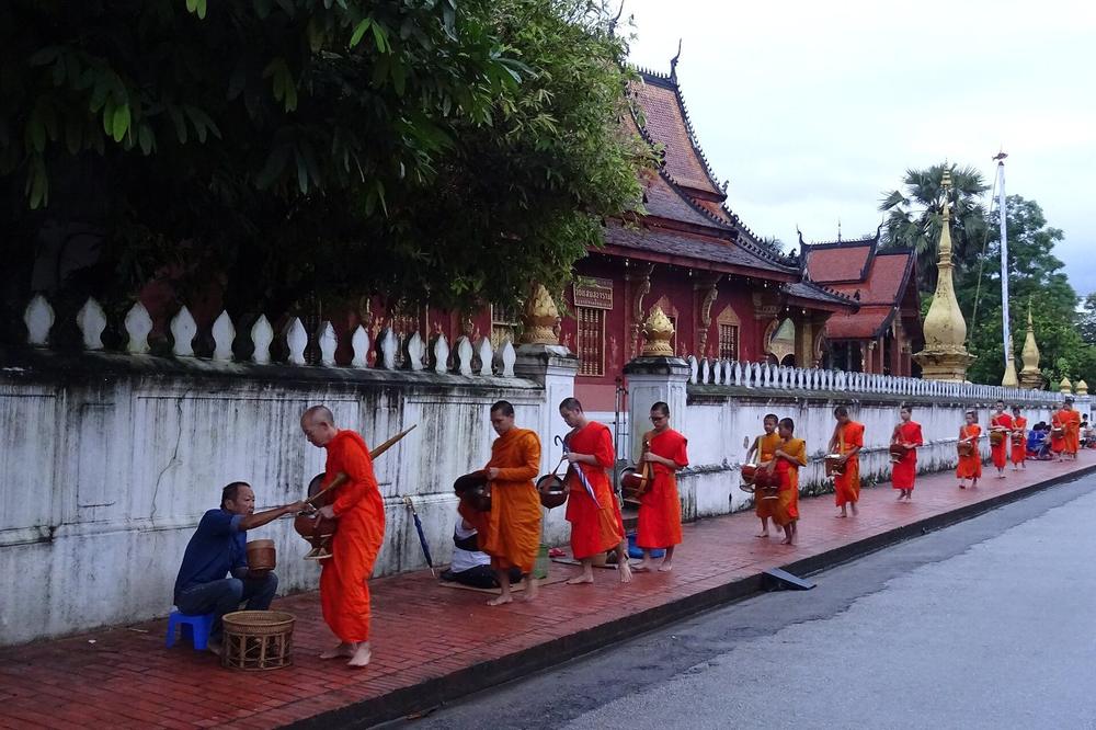 Novice monks walking a town street in single file at first light Novice monks walking a town street in single file at first light