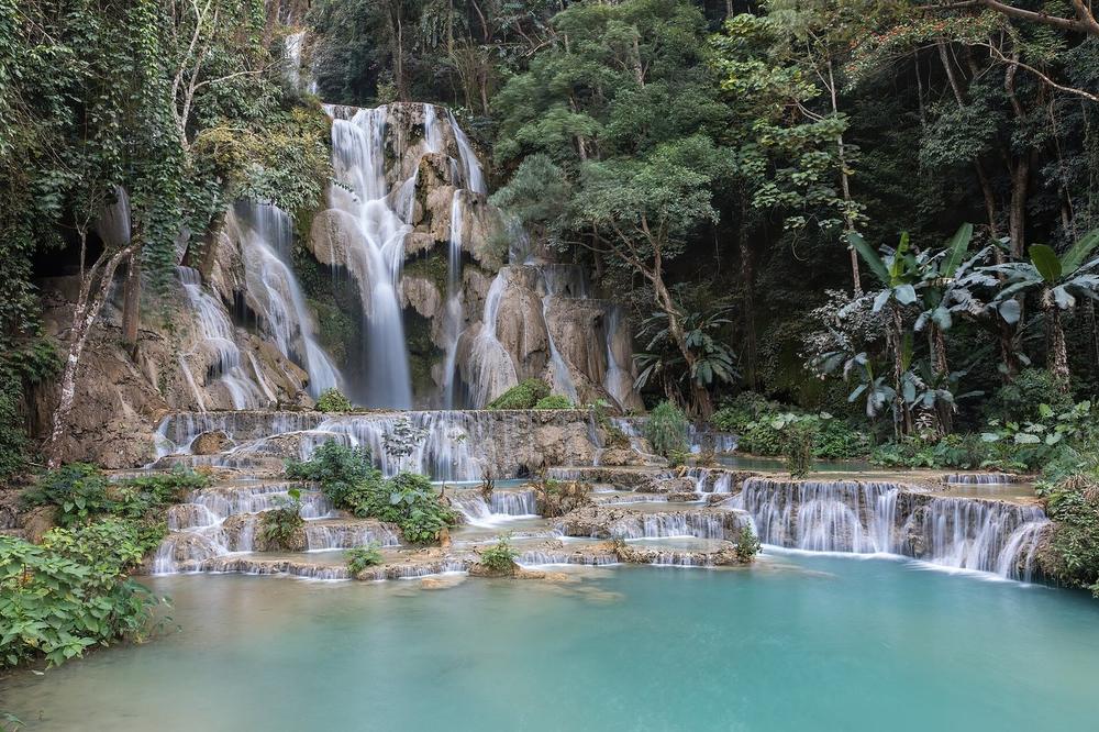 Pale blue pools stepping down through forest below a waterfall Pale blue pools stepping down through forest below a waterfall